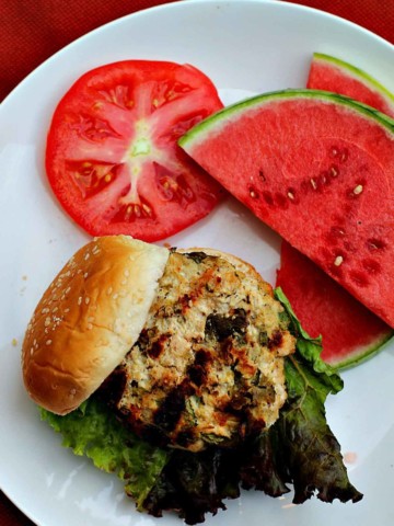 Southwest ground chicken burgers with a slice of tomato and watermelon for a side.