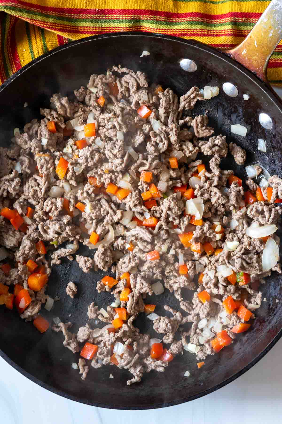 Cooking meat and vegetables to make fried tacos.