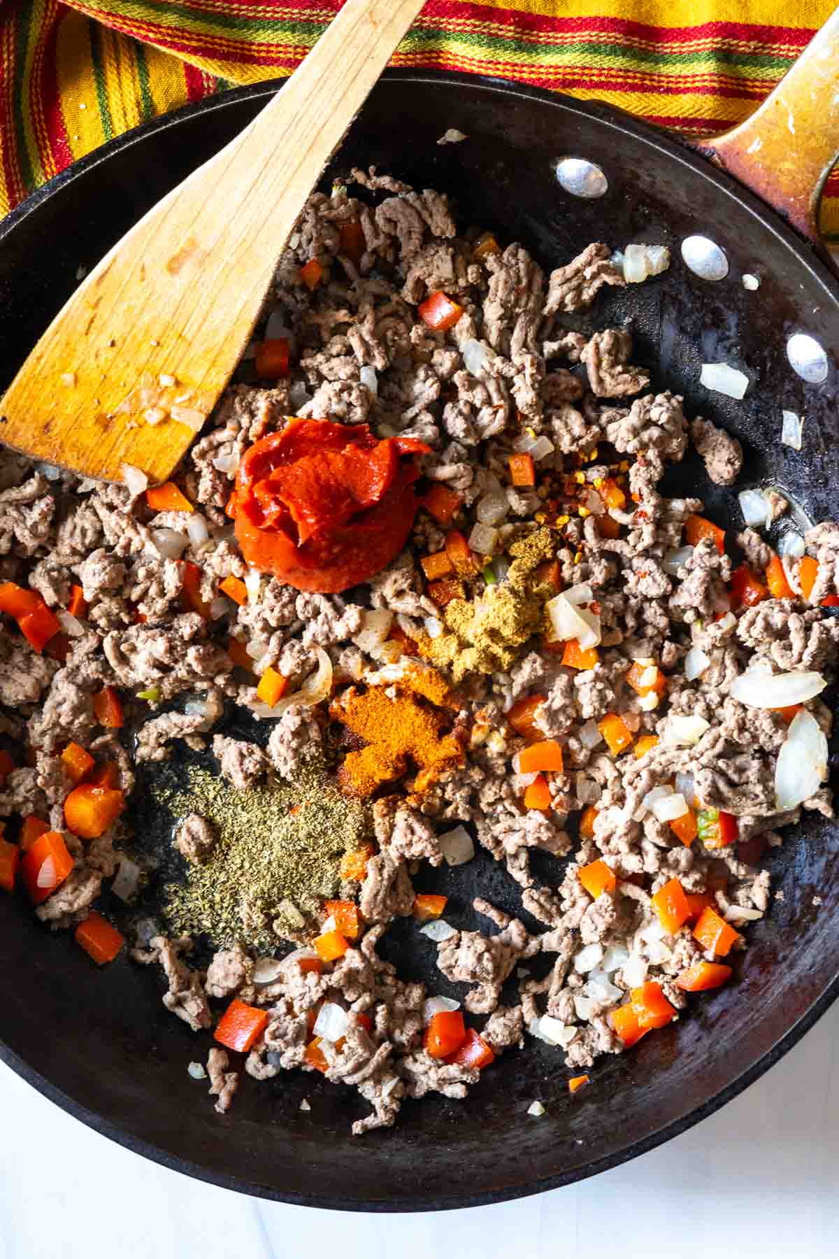 Adding seasonings to ground beef to make fried tacos.