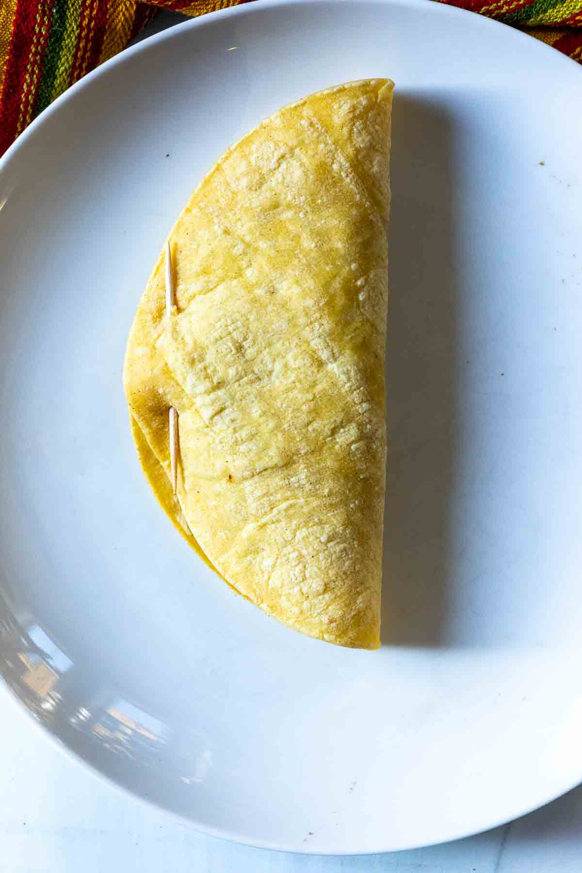 Folding a corn tortilla and securing with a toothpick to make fried tacos.