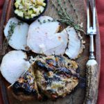 Pork loin roast on a cutting board with quick pickled cucumber relish