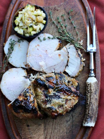 Pork loin roast on a cutting board with quick pickled cucumber relish