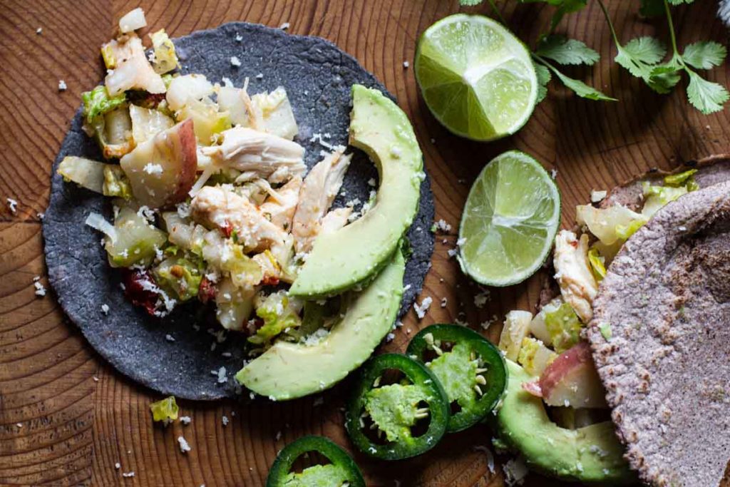 Chicken and potato tacos with avocado and limes.