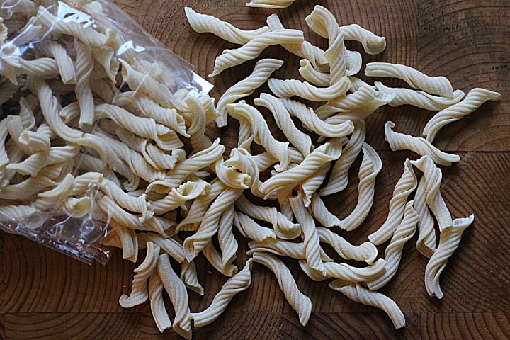 Dried garganelli pasta on a wood cutting board