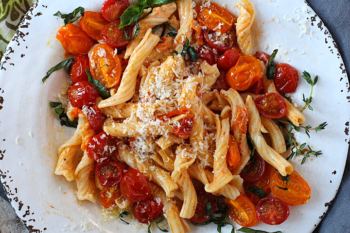 Pasta tossed with slow roasted cherry tomatoes topped with fresh basil and parmesan cheese