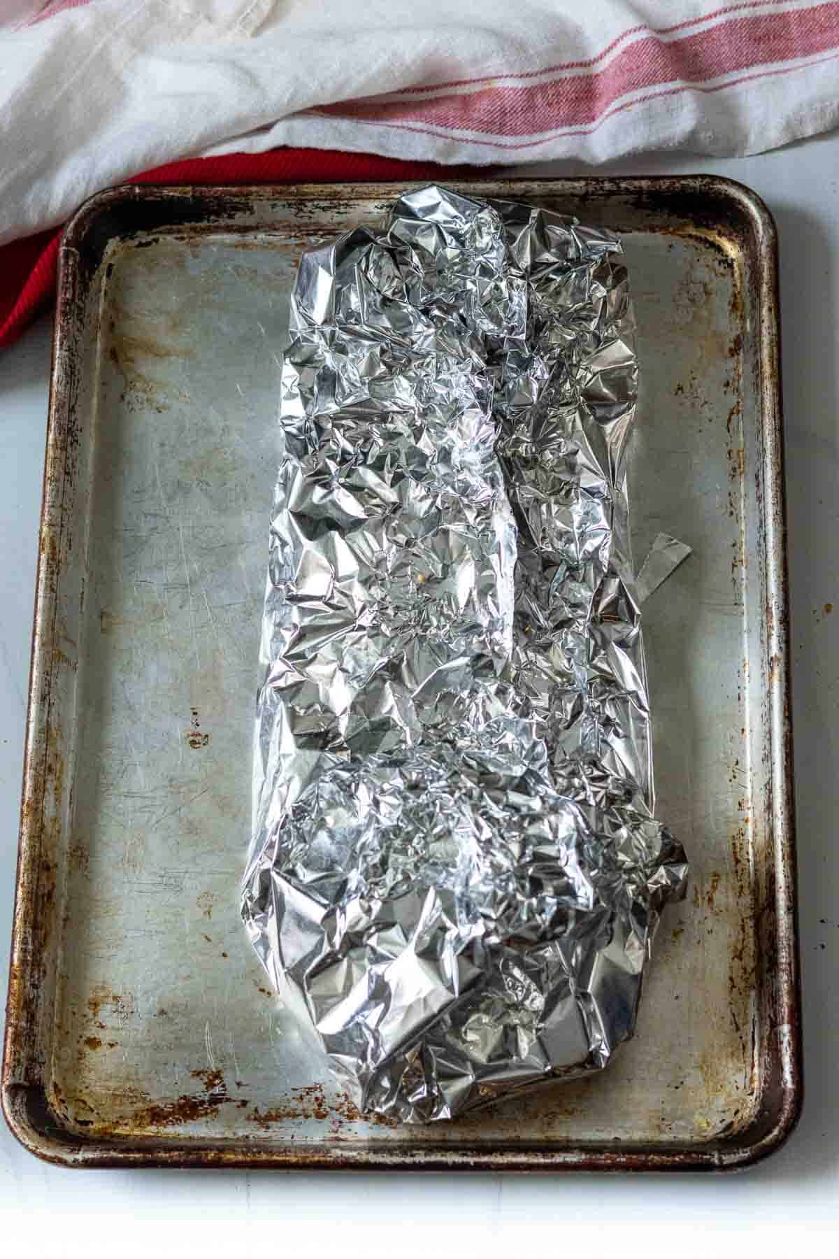 A rack of ribs wrapped in foil ready to bake in the oven.