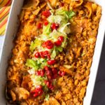 Baked chicken taco casserole topped with lettuce and tomatoes.