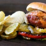 Bison burger with potato chips and spicy pickles.