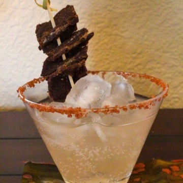 Cocktail glass with salty dog cocktail garnished with pink sea salt and beef jerkey