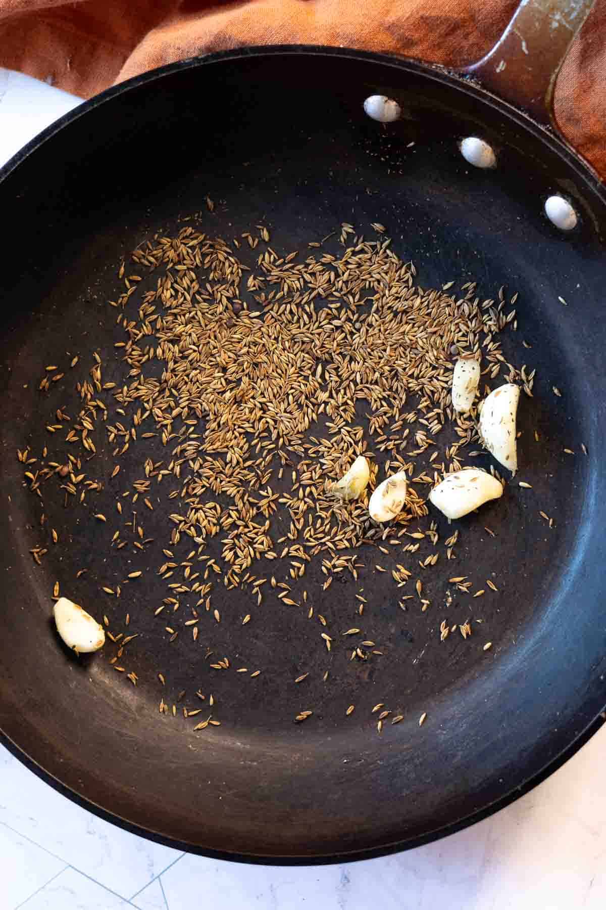 Step 2 to make red chile sauce, toasting cumin seeds and garlic.