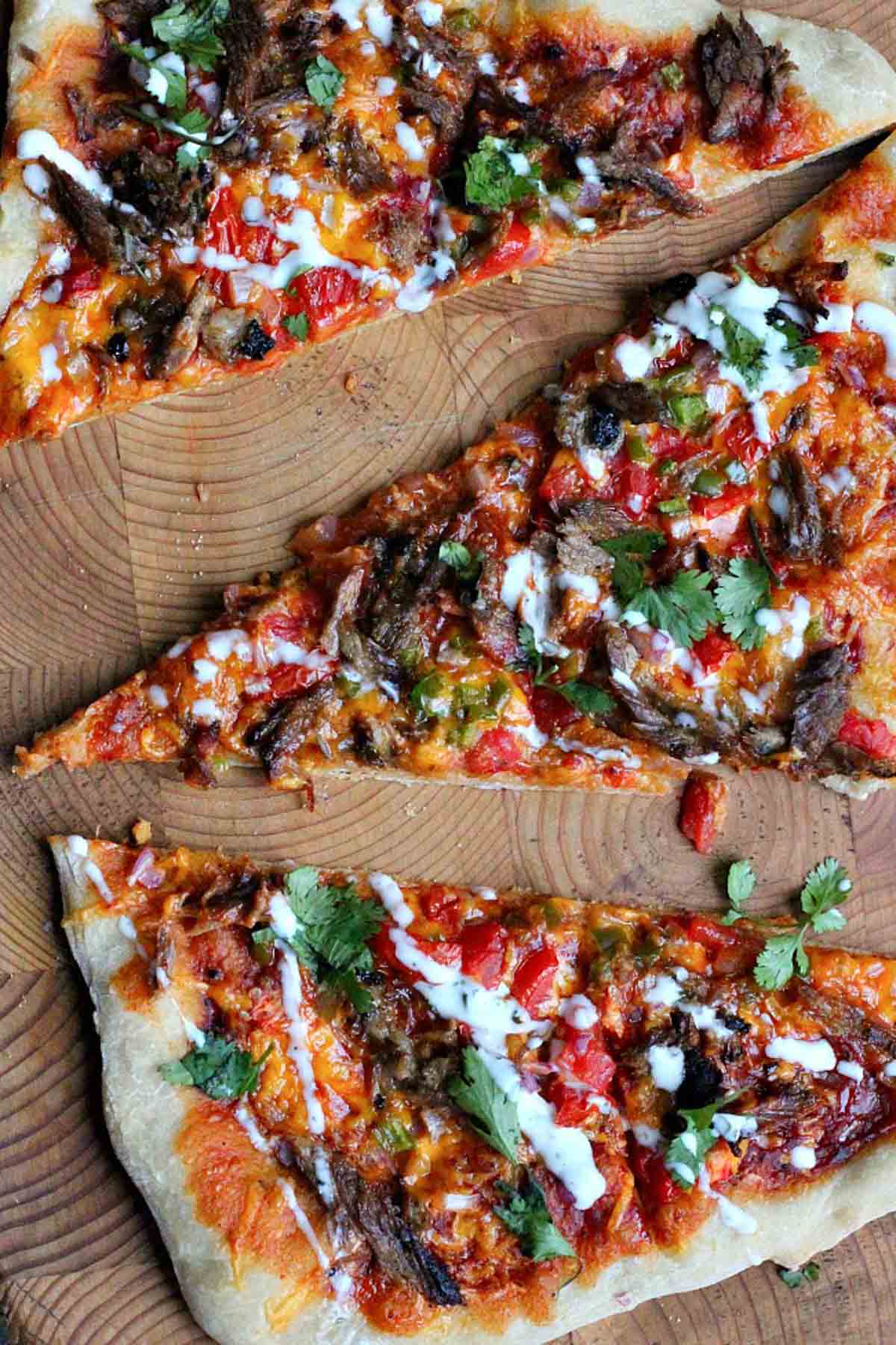 Slices of bbq brisket pizza drizzled with ranch dressing.