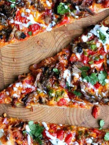 Three slices of brisket pizza on a cutting board.