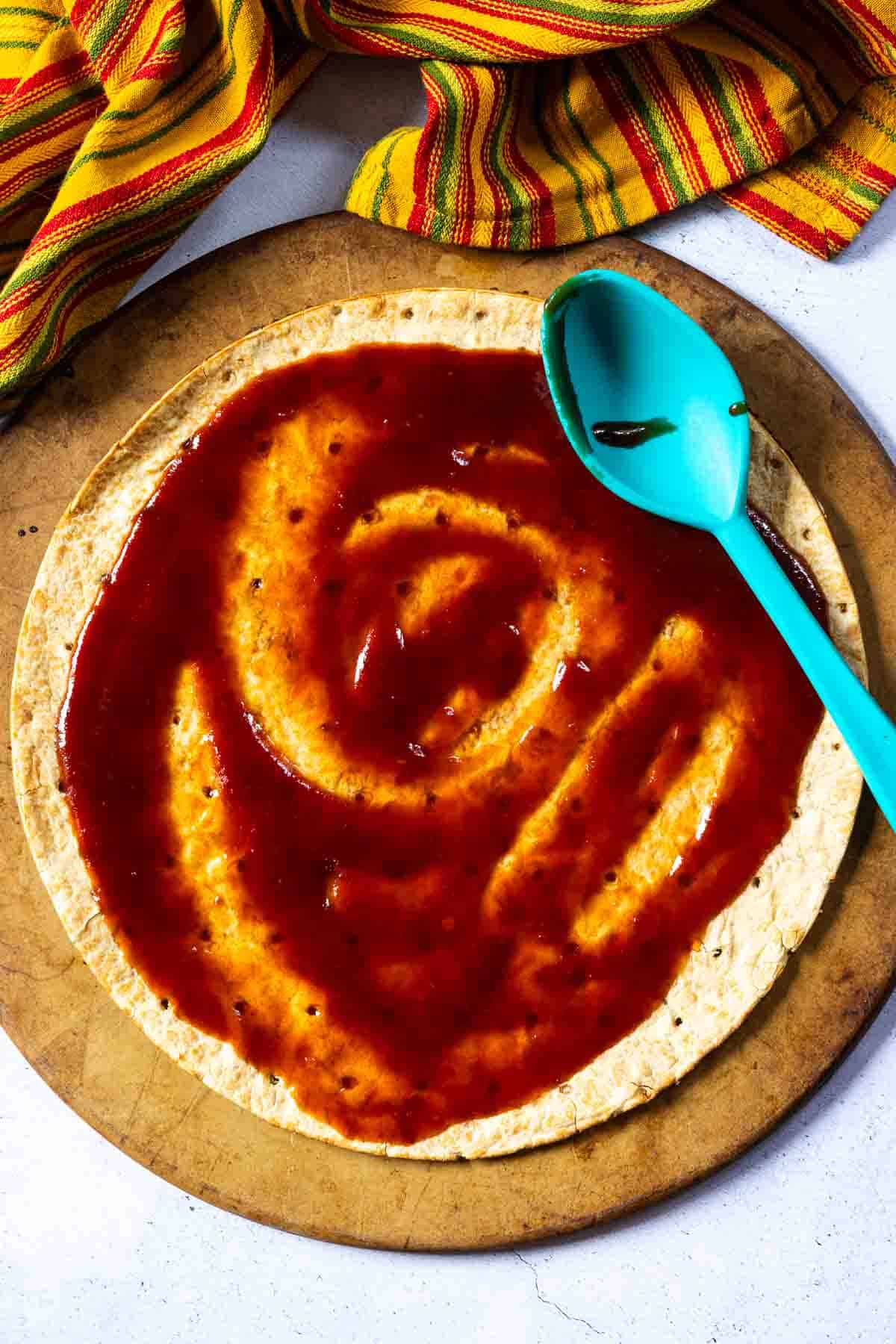 Step 1: Spreading bbq on pizza shell to make brisket pizza.