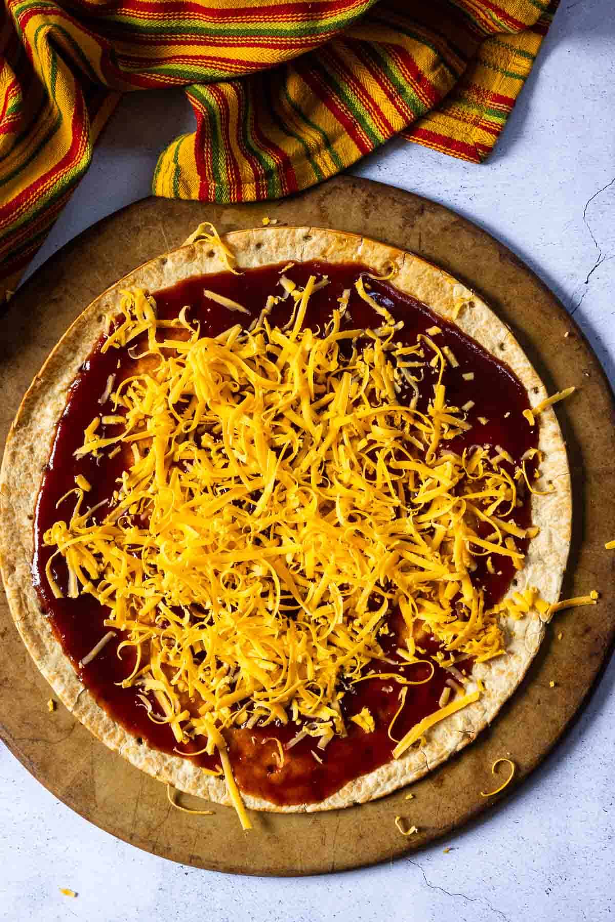 Step 2: Adding grated cheese to make brisket pizza.