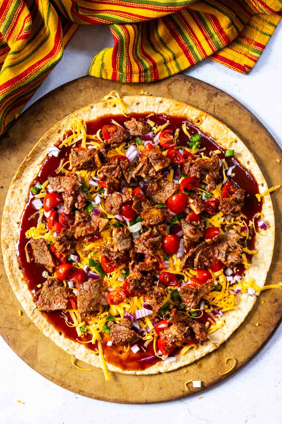 Step 5: Adding chopped brisket to pizza to make brisket pizza.