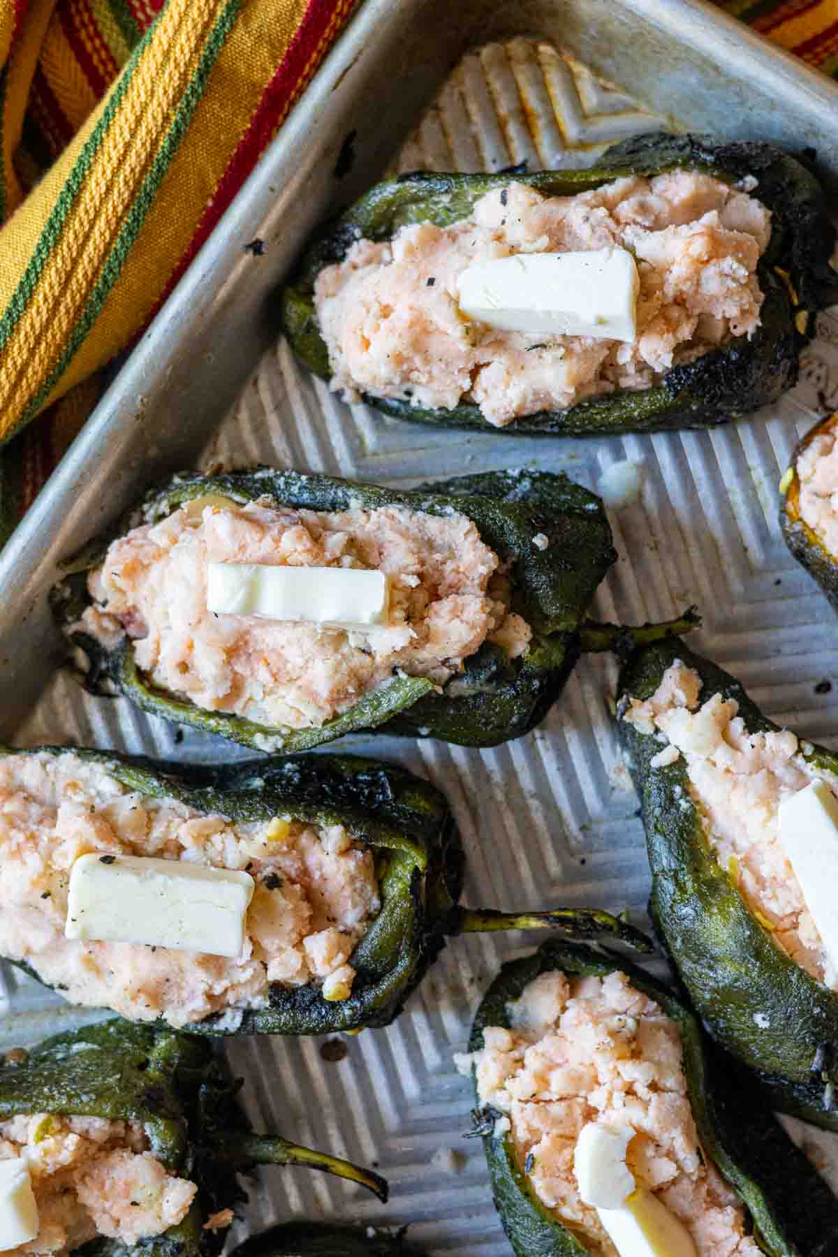 Adding butter to mashed potato stuffed poblano peppers.
