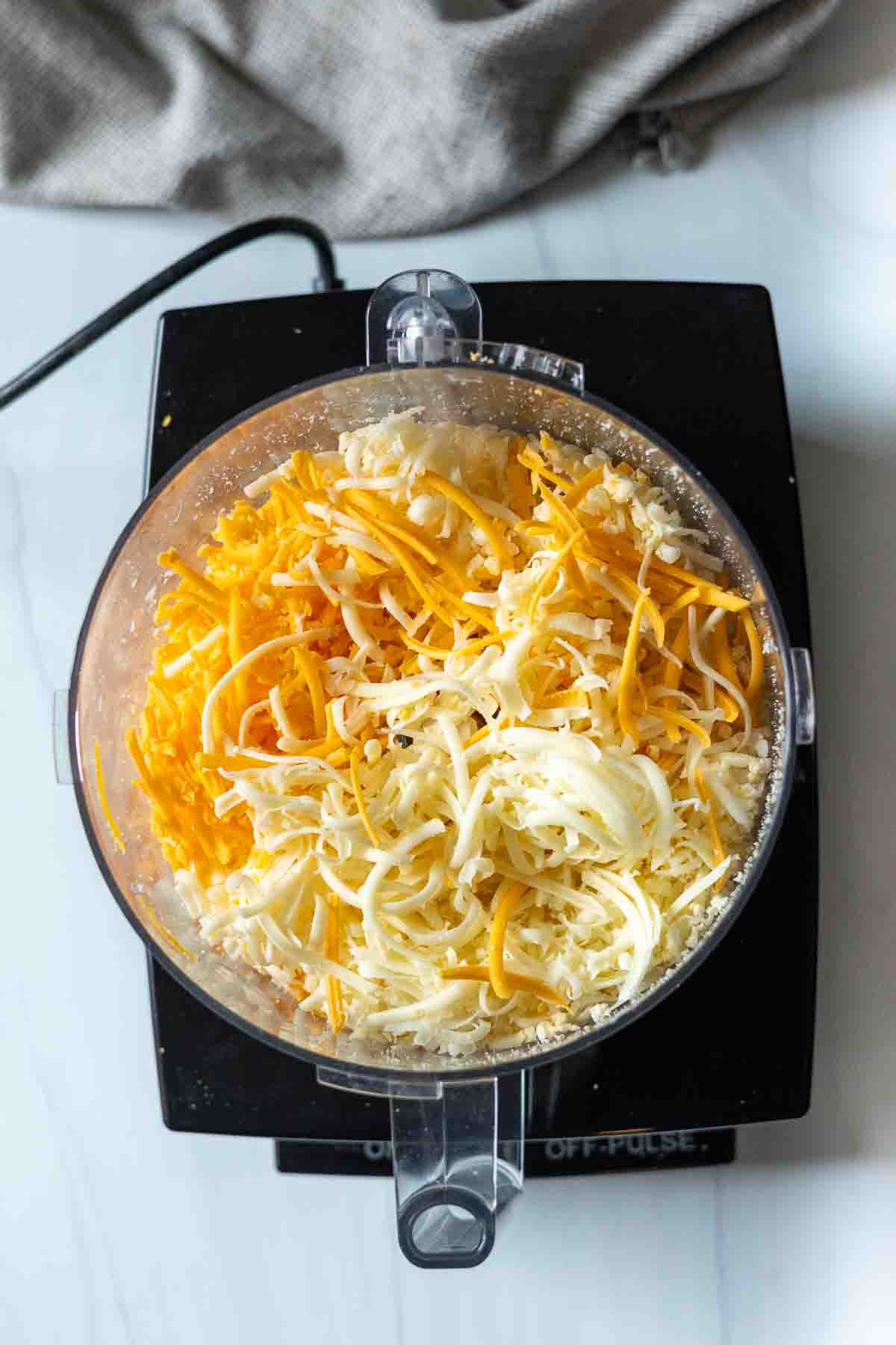 Grating cheese in a food processor to make Beer Mac and Cheese.