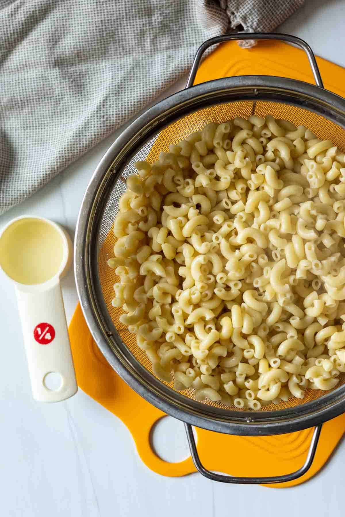 Draining pasta in a colander to make Beer Mac and Cheese.