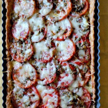 Fresh tomato tart with gruyere cheese in a rectangular tart pan.
