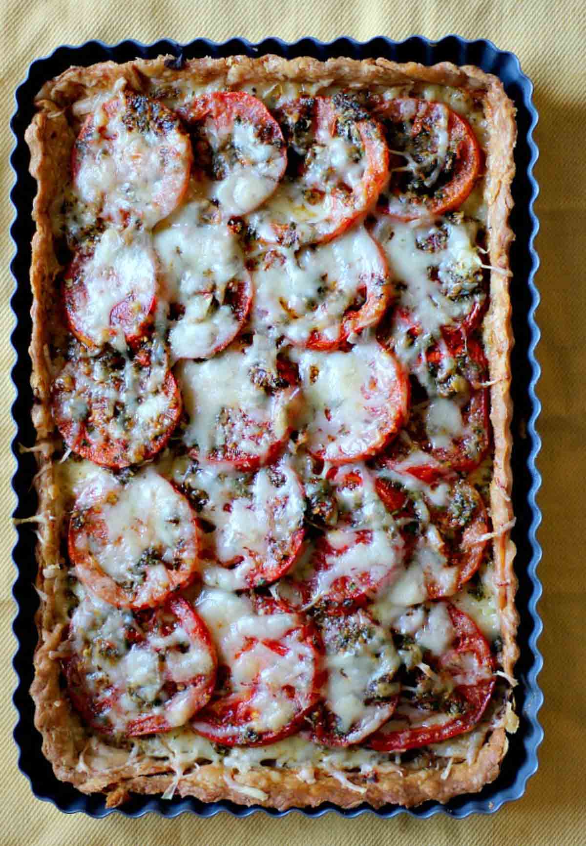 Fresh tomato tart with gruyere cheese in a rectangular tart pan.