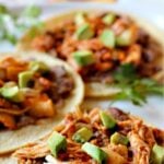Chicken tinga tacos with chorizo and beans topped with chopped avocado