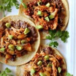Tinga chicken tacos with toppings, served on a white platter.