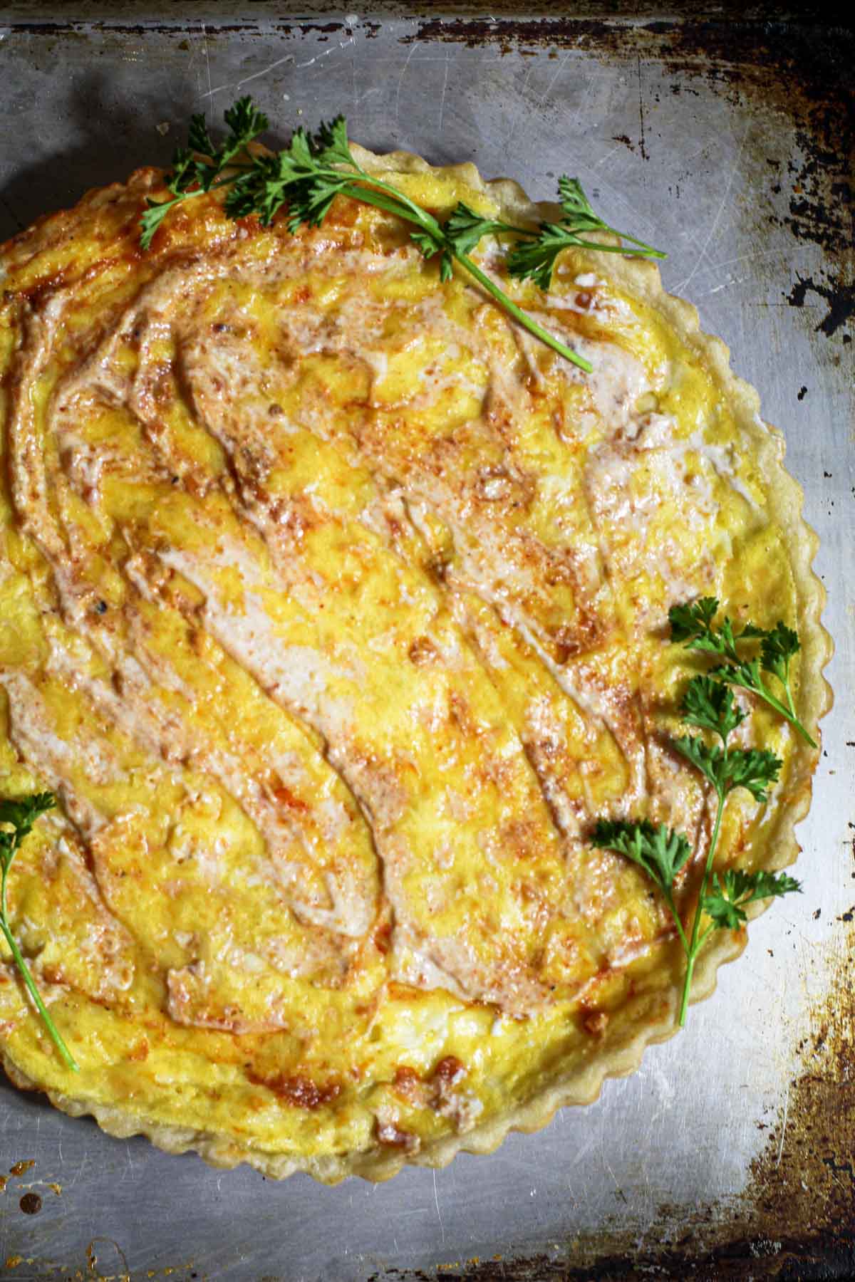 Crab quiche on a sheet pan garnished with parsley.