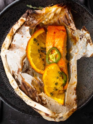 Salmon in parchment topped with oranges, jalapenos and thyme