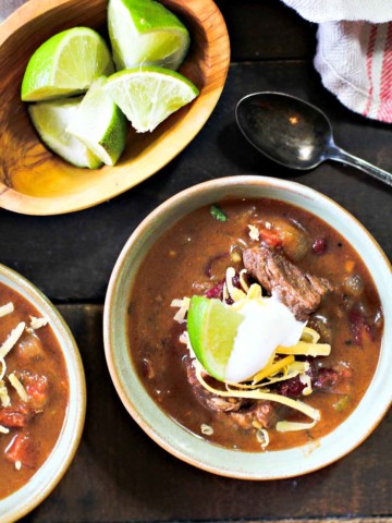 Bourbon Beef and Beef Chili garnished with sour cream and a wedge of lime.