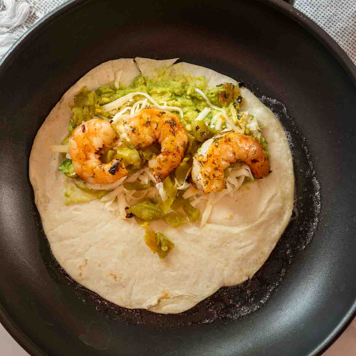 Frying shrimp quesadillas in a pan.