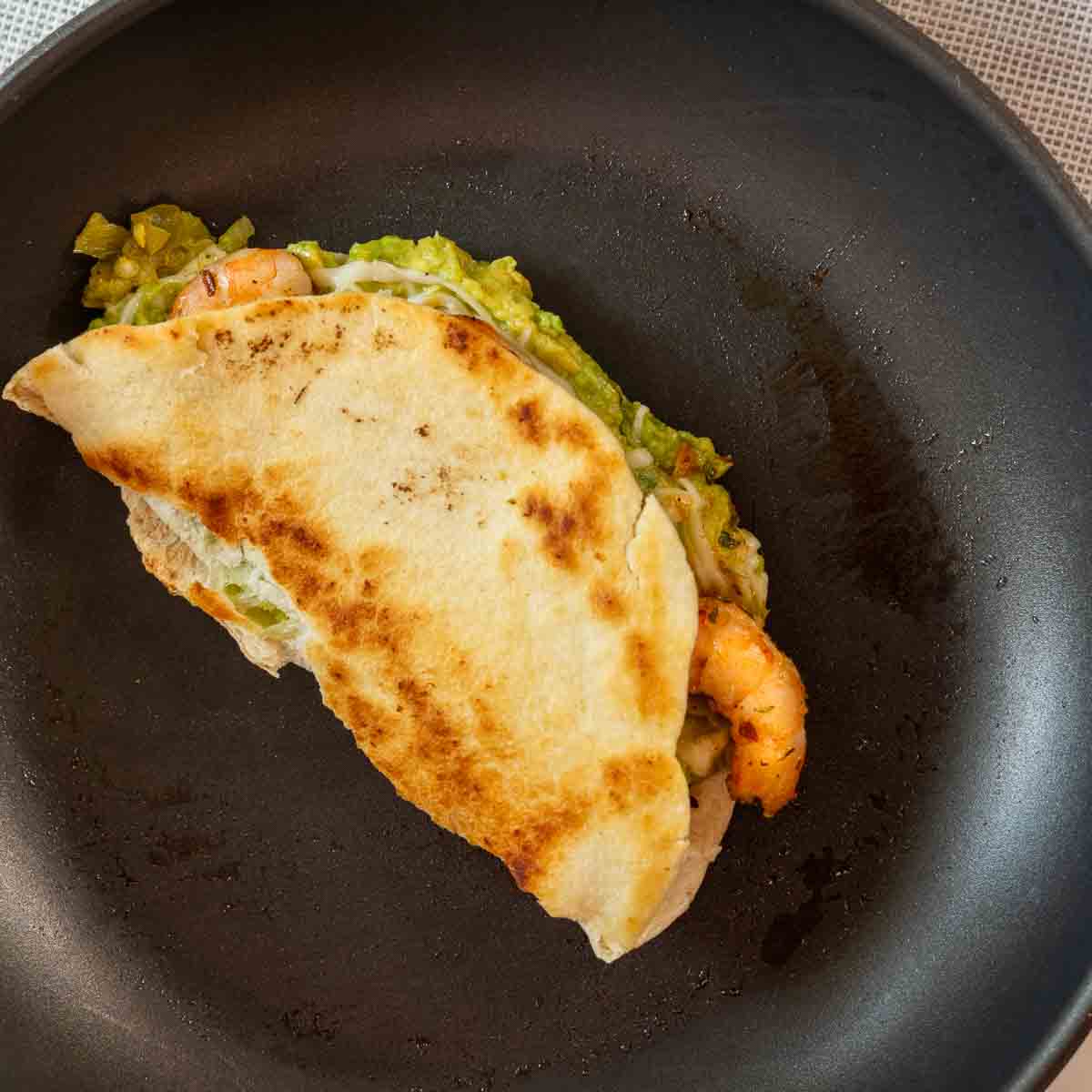 Frying shrimp quesadillas in a non-stick pan.