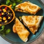 Shrimp Quesadillas on a blue plate served with black bean and corn salsa.