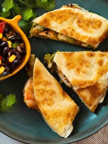 Shrimp Quesadillas on a blue plate served with black bean and corn salsa.