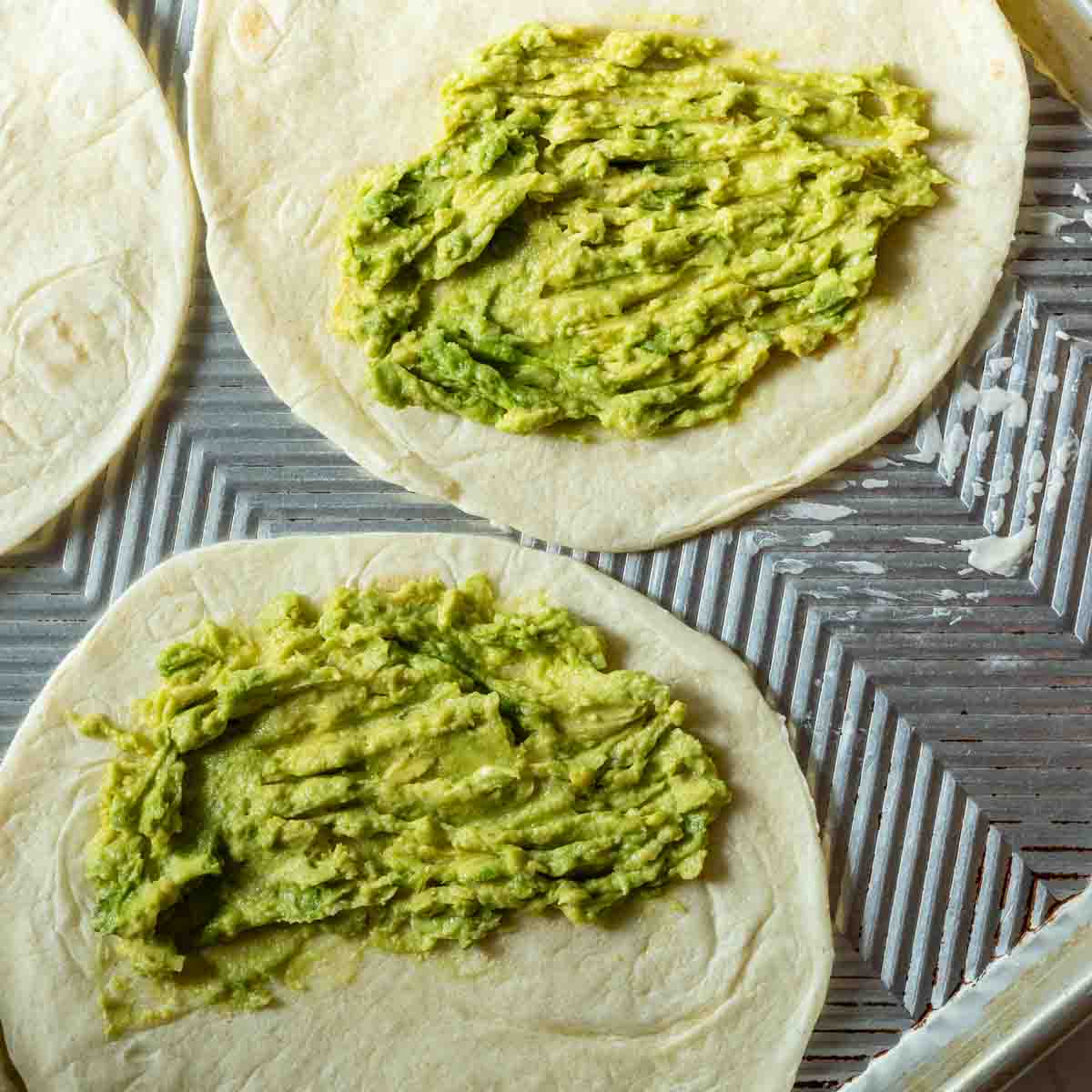 Smashed avocado on a flour tortilla to make shrimp quesadillas.