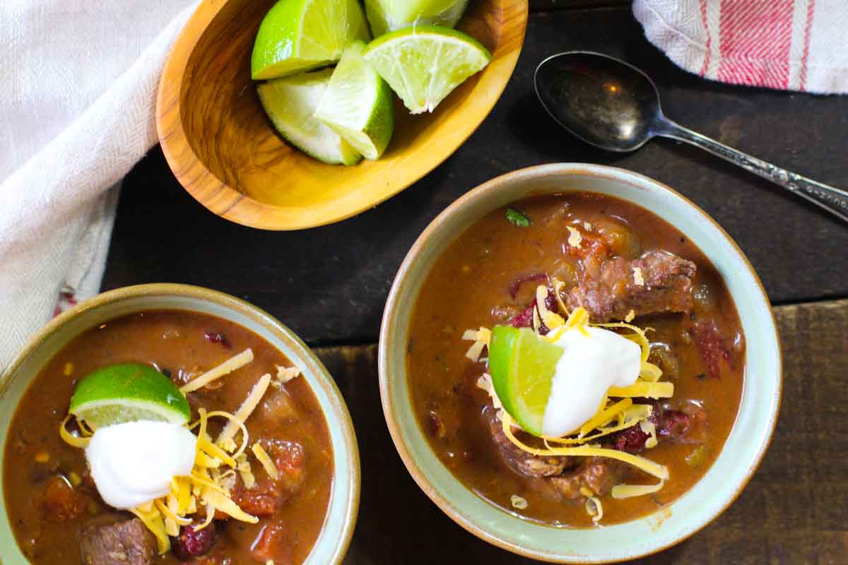 Beef chili with beans garnished with sour cream and lime.