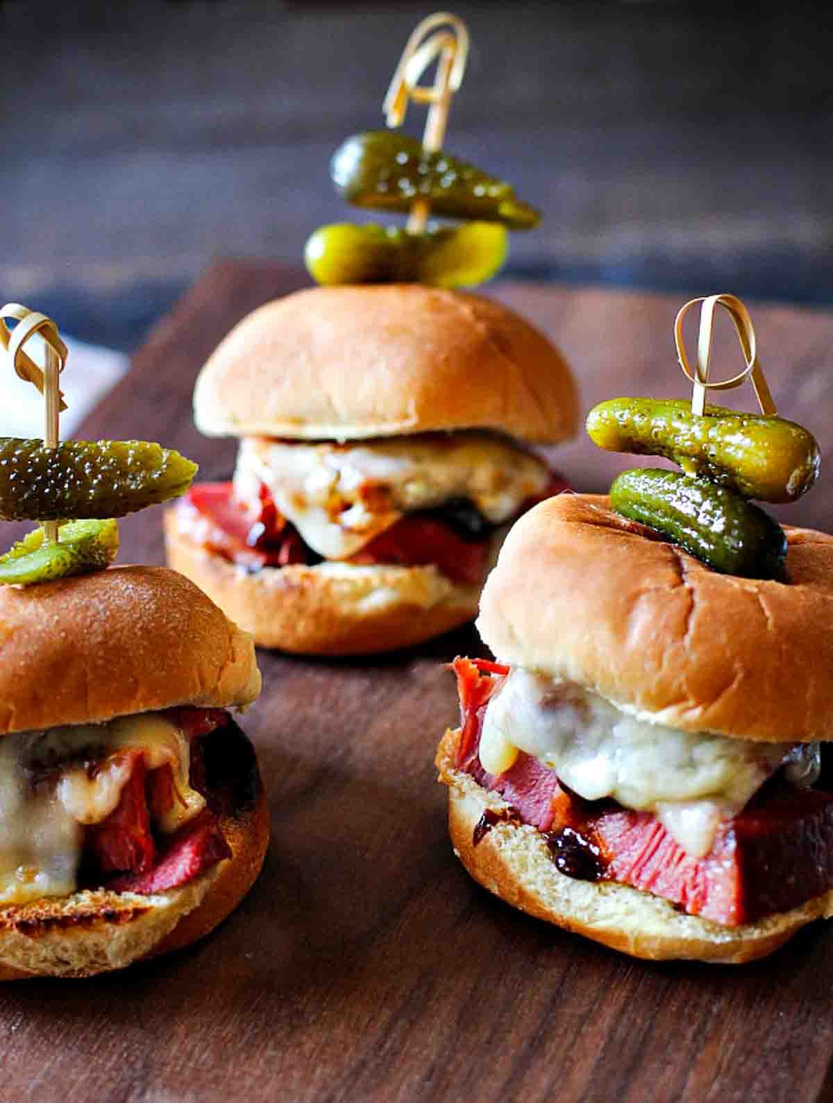 Molasses glazed corned beef sliders on a wooden cutting board.