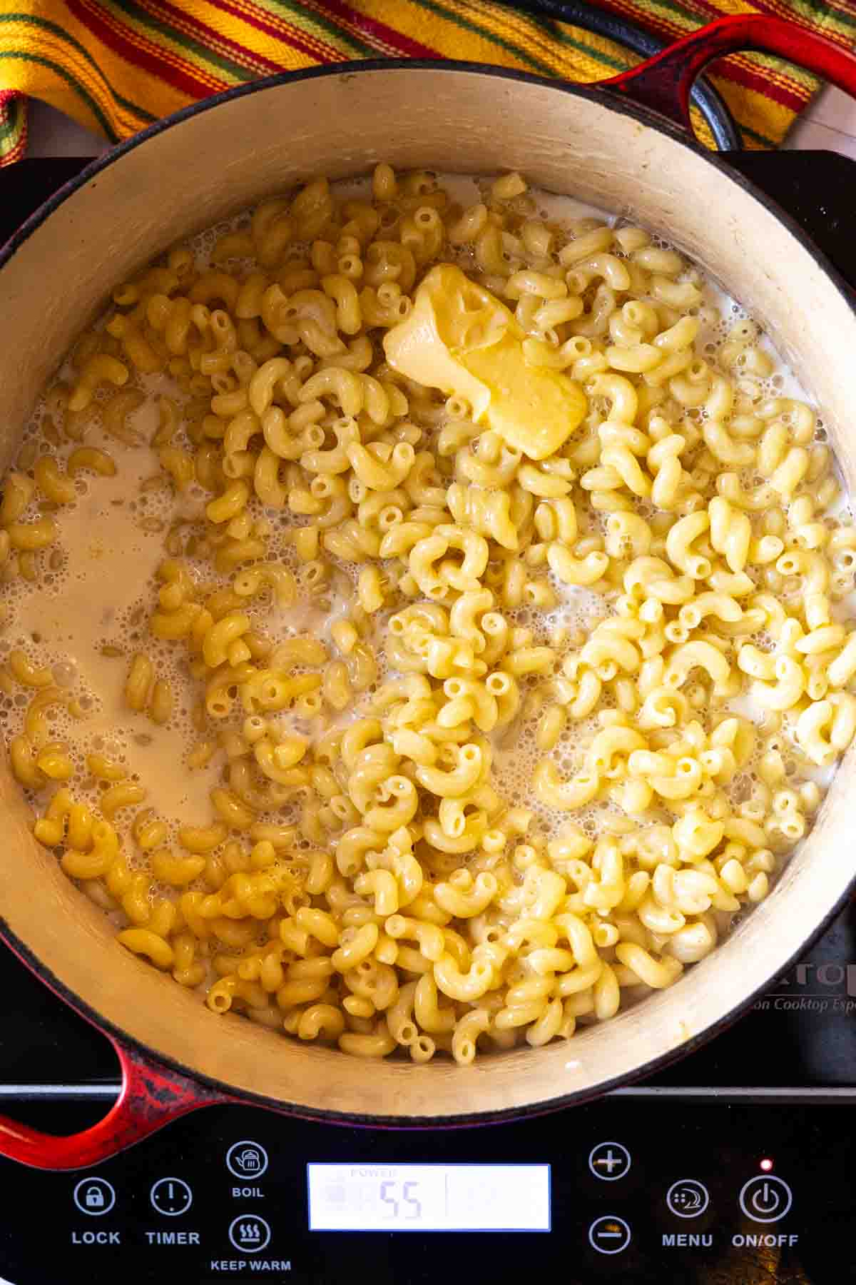 Step 4: Adding evaporated milk and butter to cooked elbow macaroni.