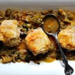 One pan crispy chicken thighs with tomatillo wine sauce on a white serving platter with an antique serving spoon
