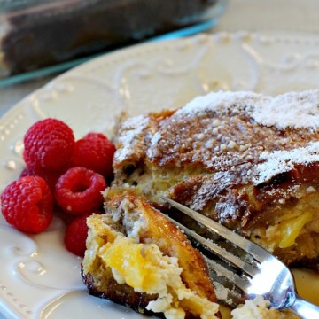 A slice of mango cream cheese stuffed french toast with a side of fresh raspberries