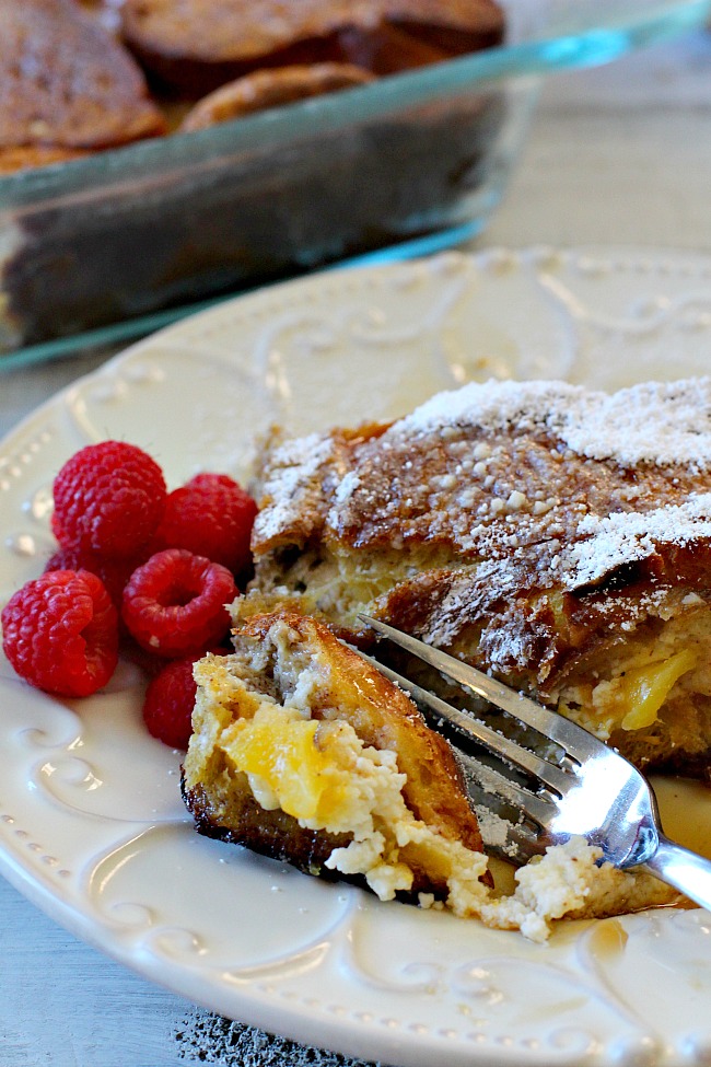 A slice of mango cream cheese stuffed french toast with a side of fresh raspberries