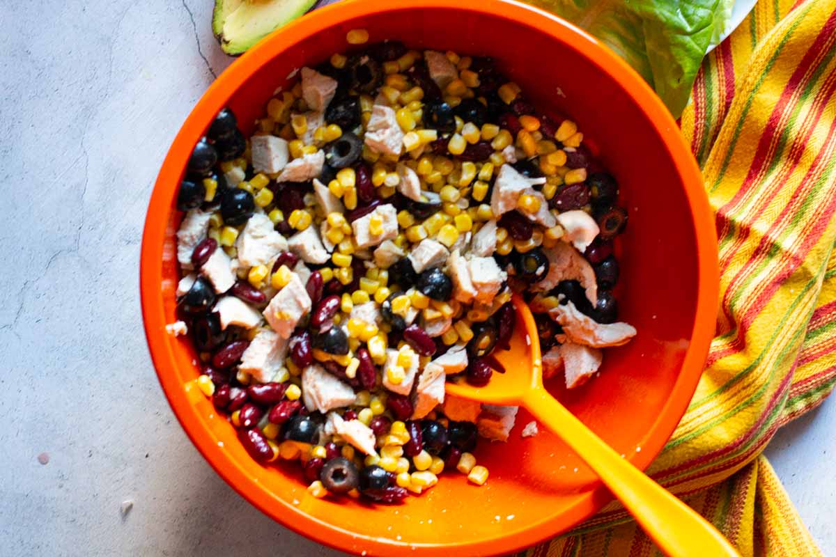 Stirring Mexican chicken salad ingredients in a bowl.