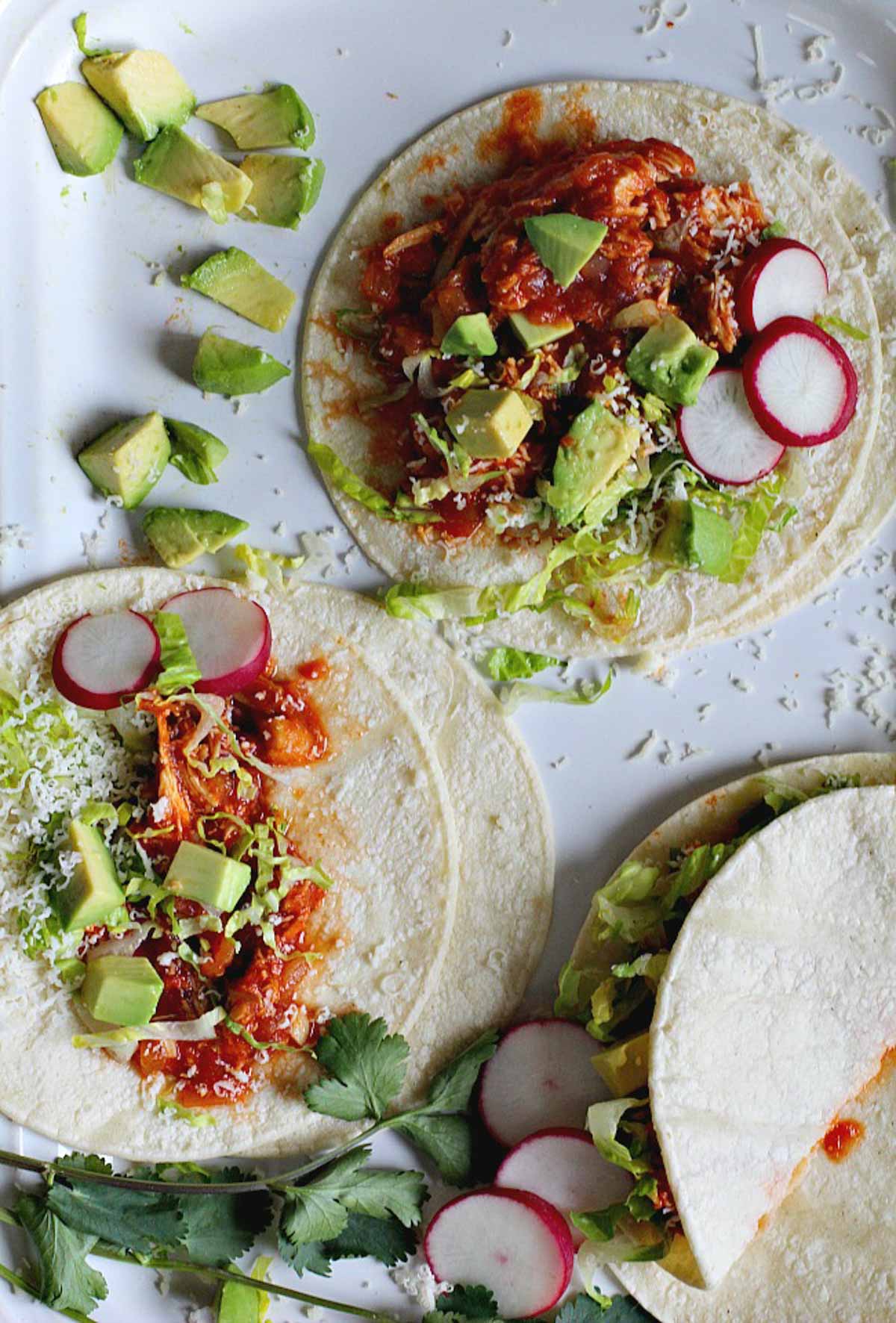 Chicken tacos on flour tortillas with radishes and avocado.