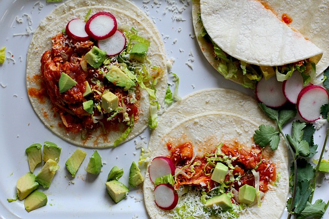 Warm flour tortillas filled with chicken and topped with romaine lettuce, radishes and avocado for chicken soft tacos.