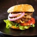 Black and blue burger with red onion, tomato and lettuce.