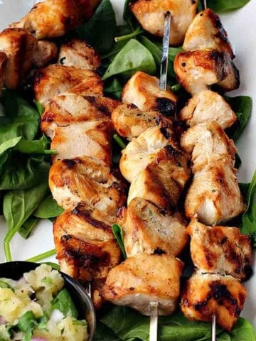 Maple syrup glazed grilled chicken breast kabobs served over spinach greens.