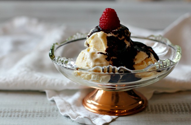 Spicy Mexican Chocolate Sauce in a class bowl with a copper stand. Topped with a fresh raspberry