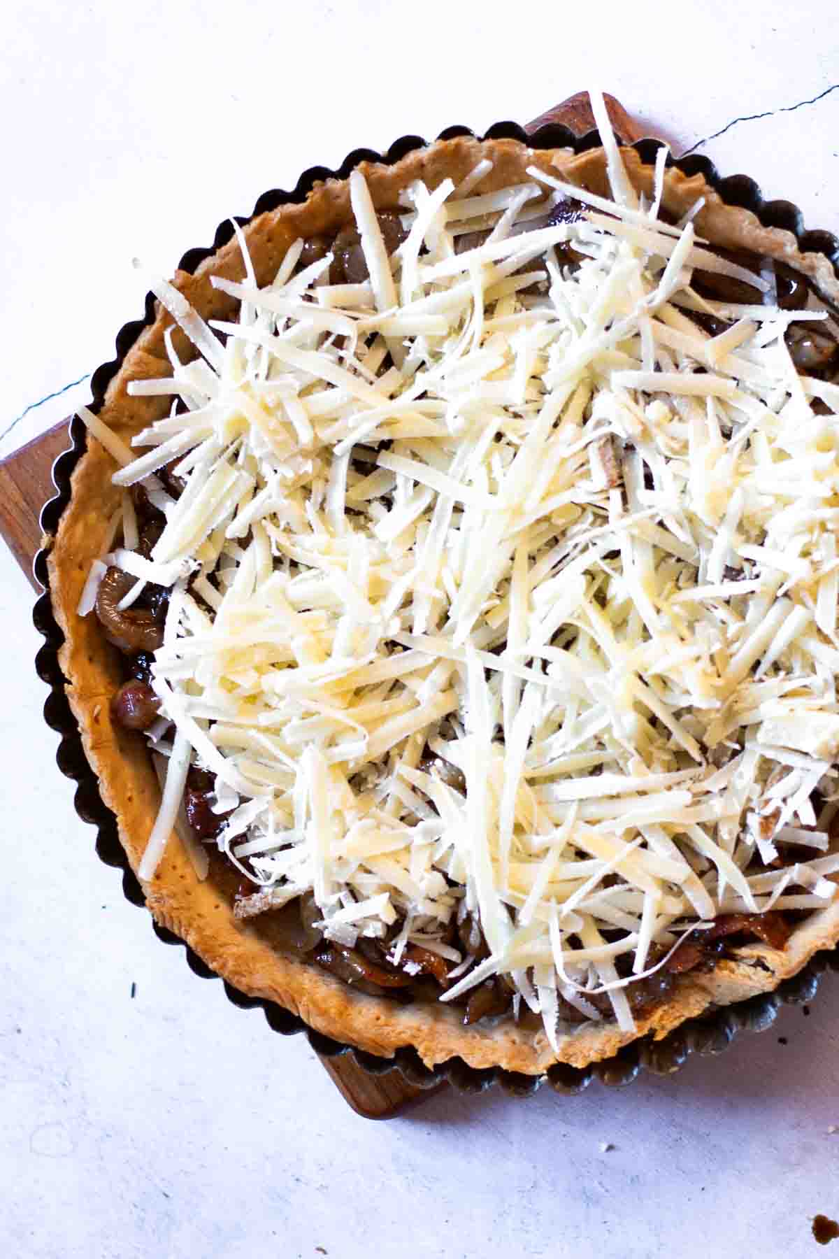 Caramelized onion tart topped with gruyere cheese ready to bake.