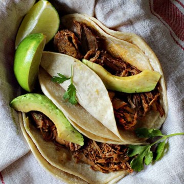 Shredded pork tacos with Achiote Sauce topped with slices of avocado.