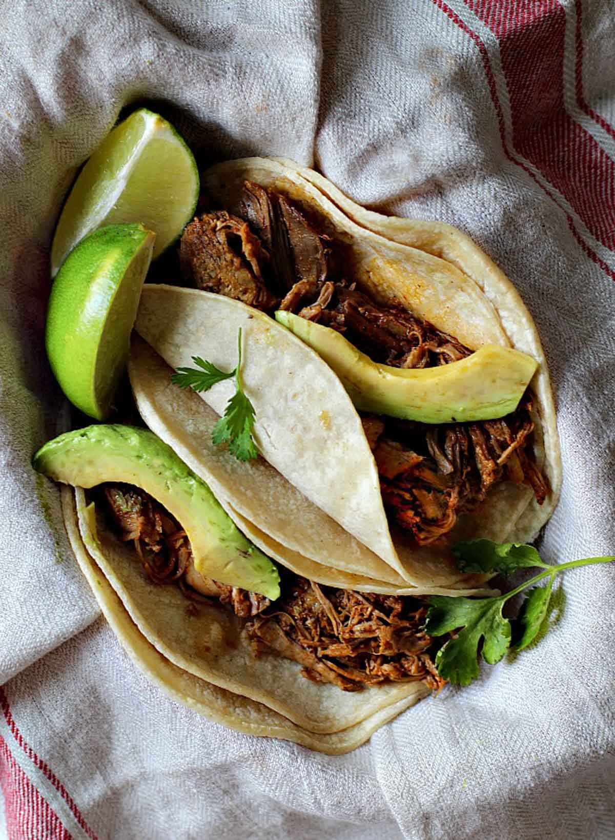 Shredded pork tacos with Achiote Sauce topped with slices of avocado.