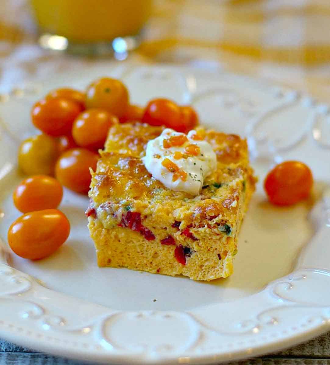 A slice of Italian breakfast casserole topped with sour cream.